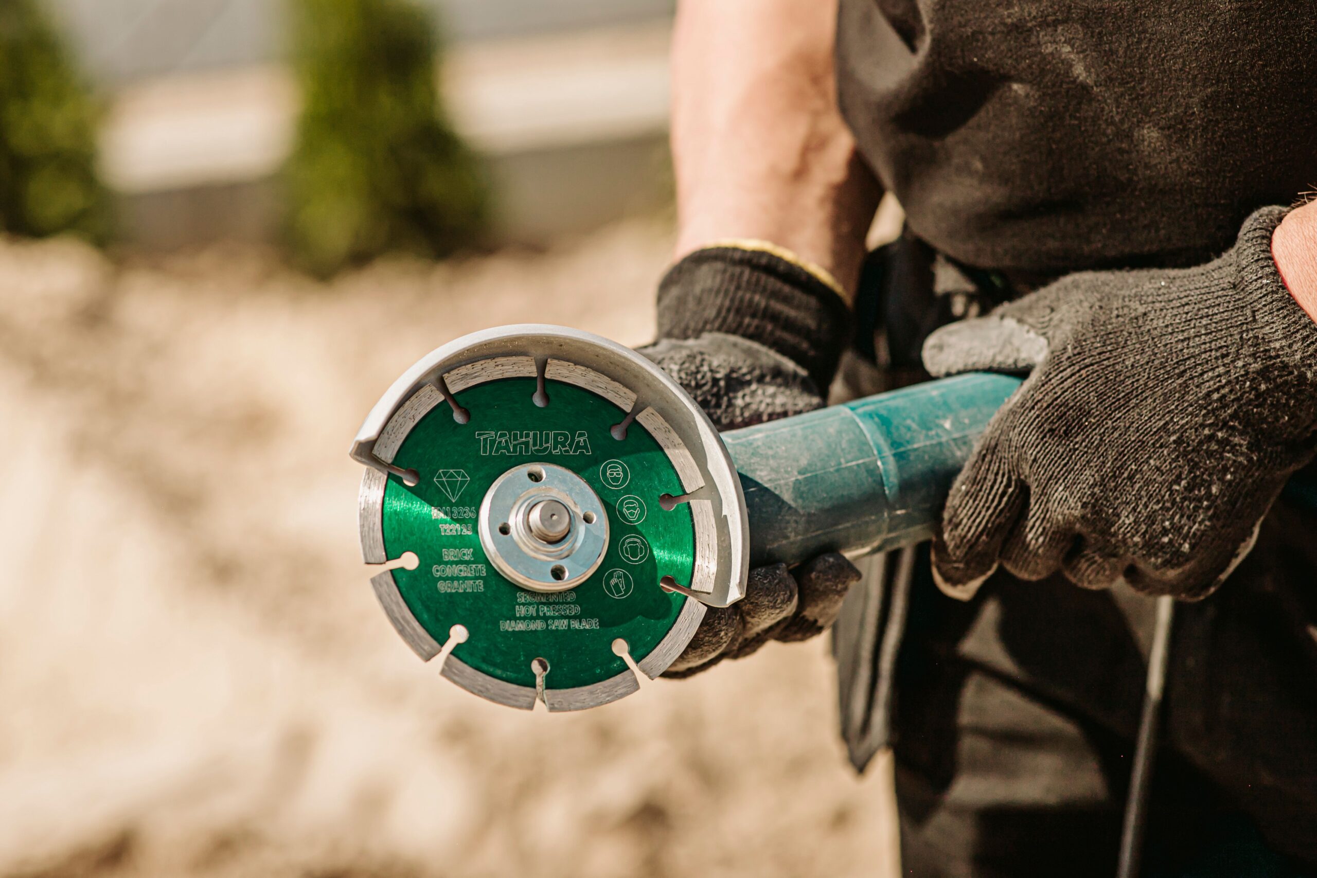 Worker using an angle grinder tool outdoors, showcasing blue-collar craftsmanship.